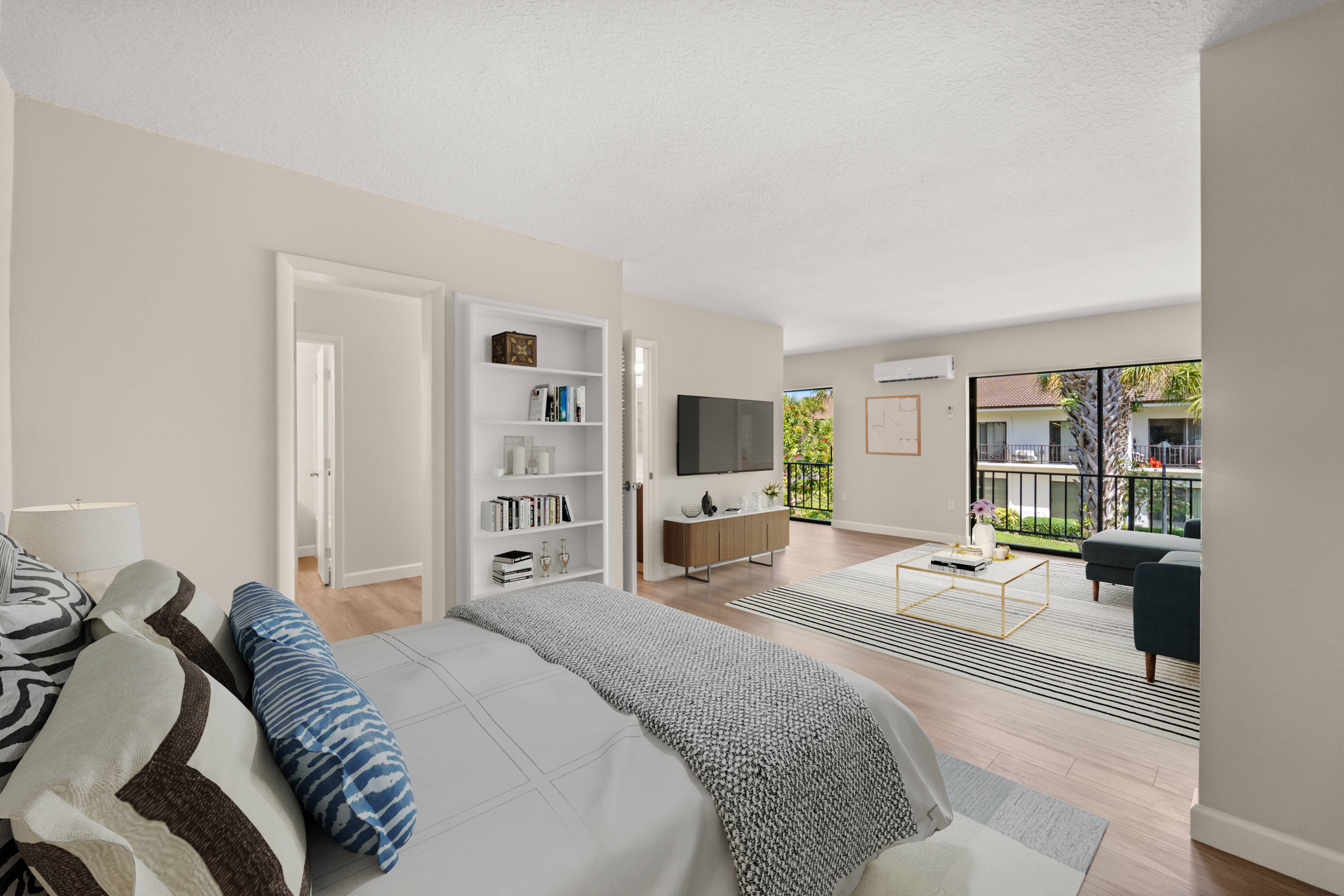 A bedroom with a large bed and a balcony overlooking the backyard.